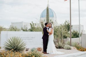 Elegant Tucson wedding portrait of a bride and groom posing together on the temple grounds with desert plants and architecture