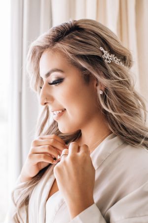 Tucson bridal portrait close-up of a bride smiling softly while adjusting her veil in natural window light.