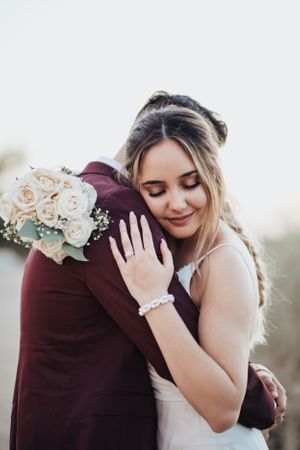 Tucson wedding portrait of a bride smiling with her bouquet while the groom hugs her from behind.