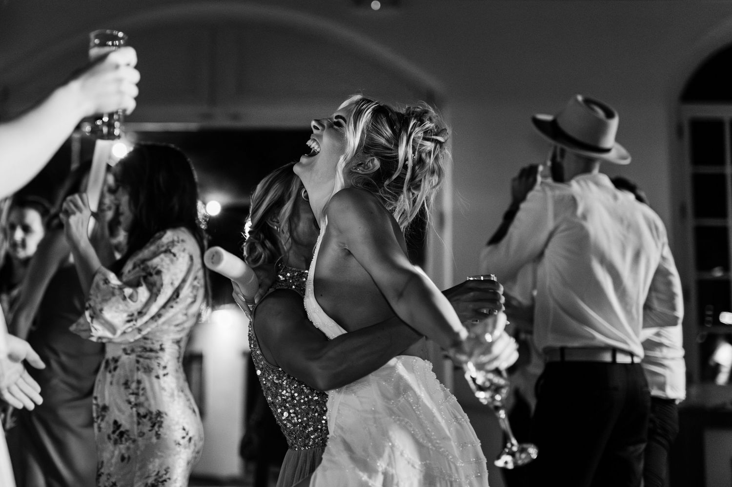 A group of people dancing and celebrating at a black and white wedding reception party.