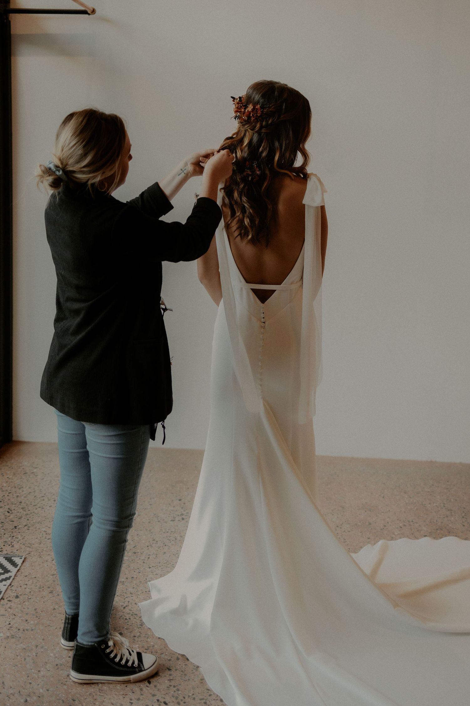 Behind the scenes of wedding dress preparation with stylist adjusting details.