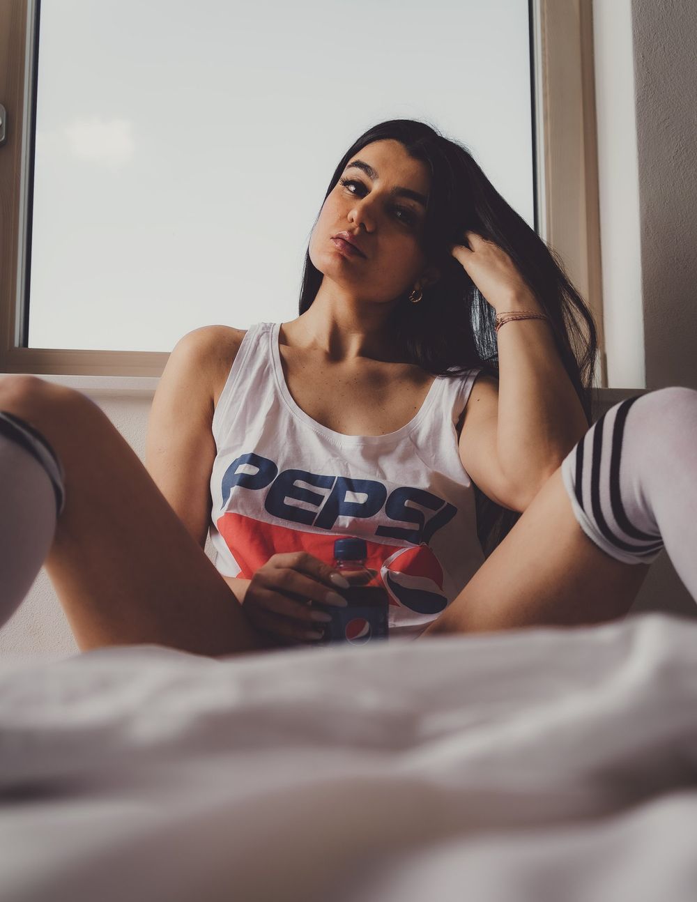 Casual portrait wearing vintage Pepsi tank top and striped socks on bed.