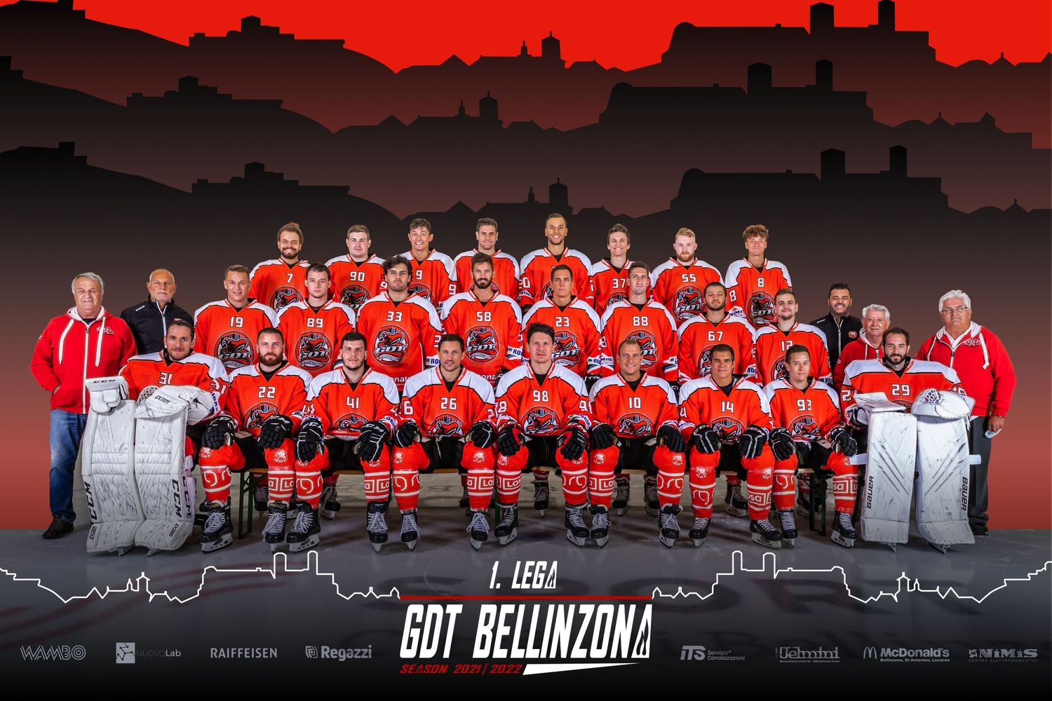 Hockey team group photo with red jerseys against dramatic red skyline backdrop.