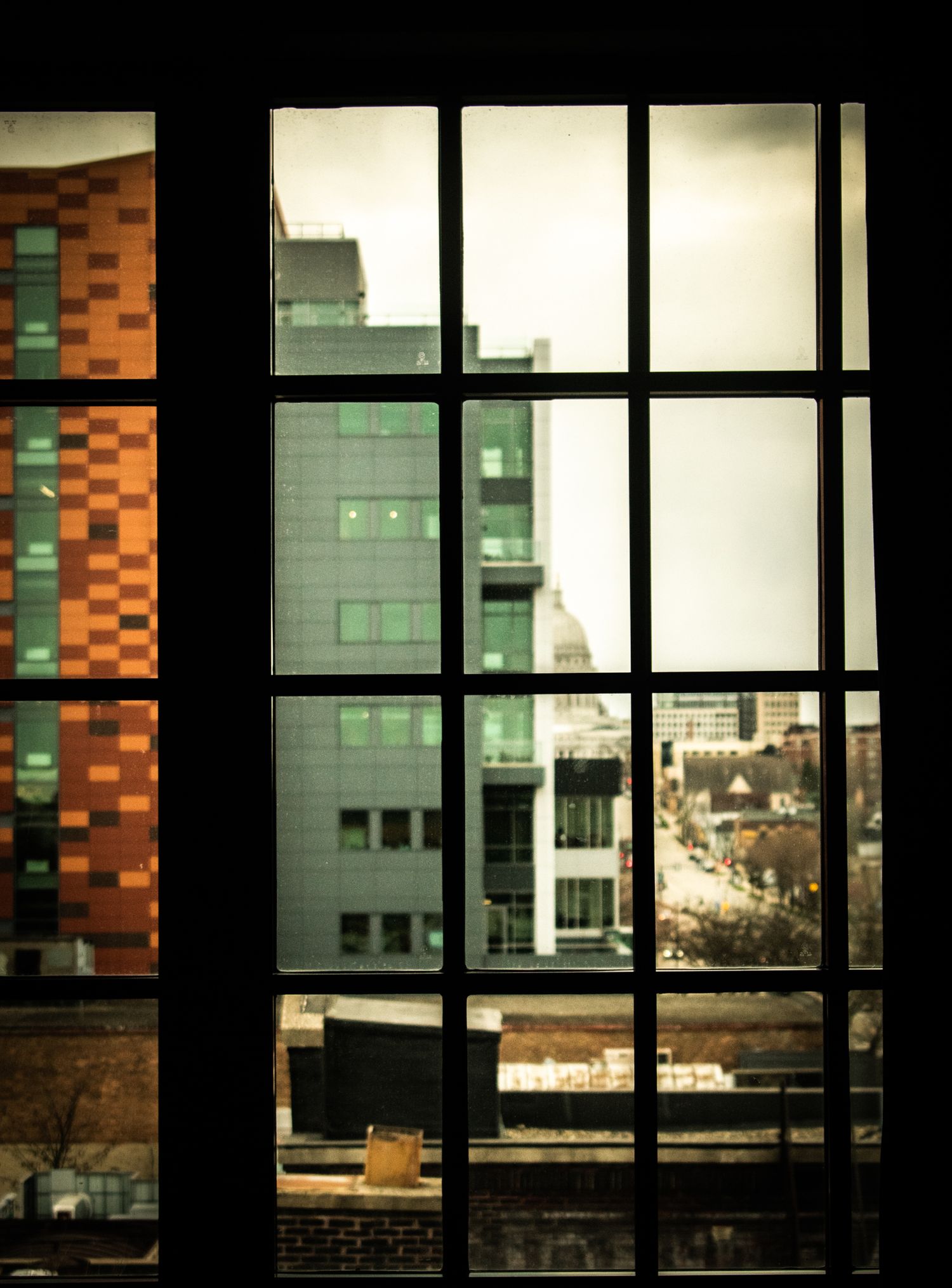 Modern office building viewed through grid window panes in urban setting.