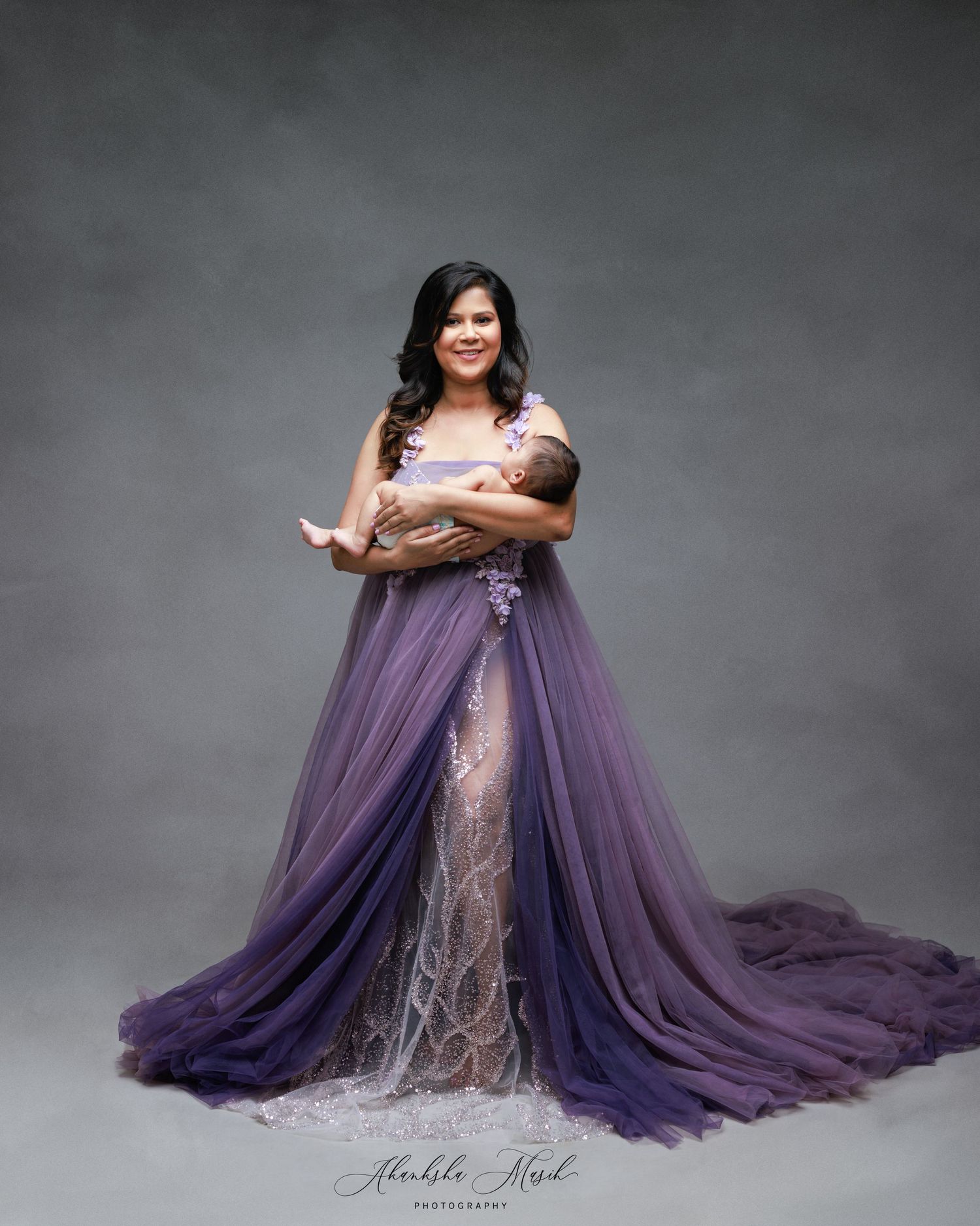 Maternity portrait in dramatic purple and lace gown against dark background.