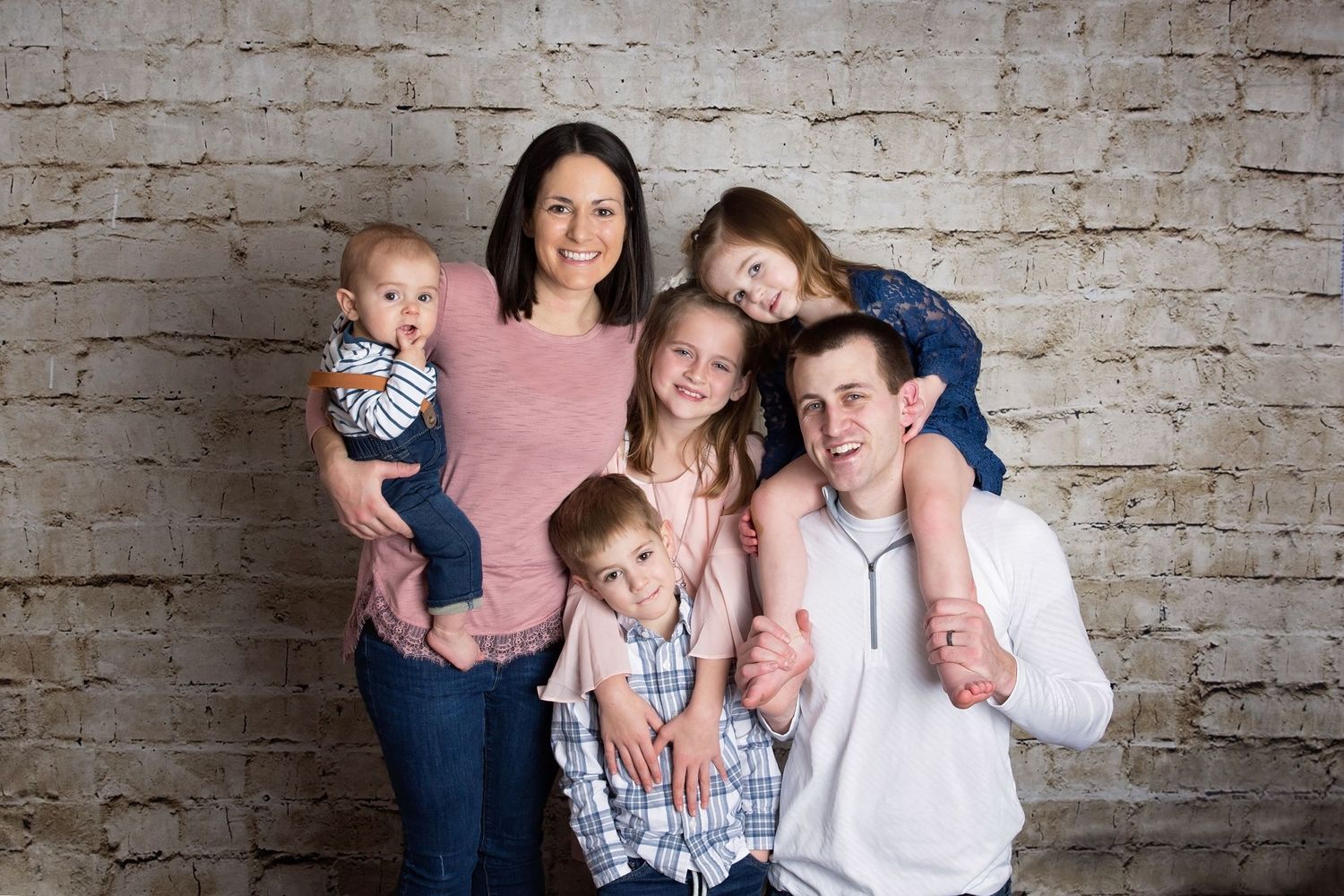 Family portrait series against a rustic brick wall background showing casual interactions and laughter.