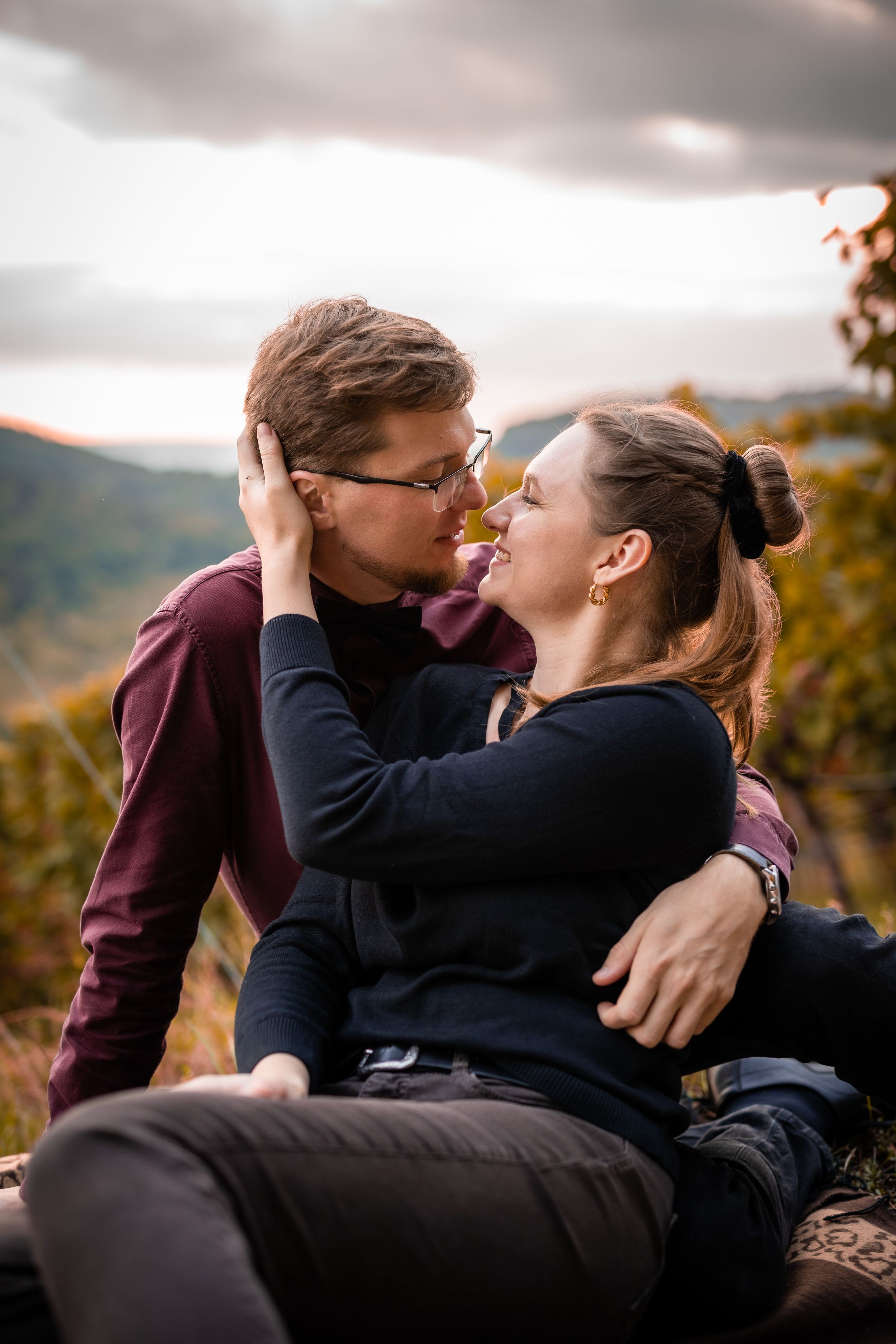 Intimate couple's portrait at sunset in autumn vineyard landscape with mountain views.
