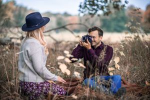 A couple having a picnic photoshoot in a fall meadow setting.