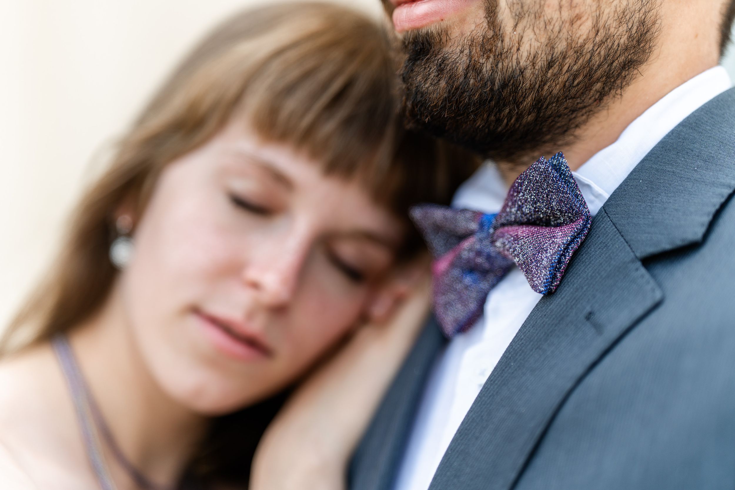 Intimate soft focus portrait showing formal attire details including bow tie and dress fabric.