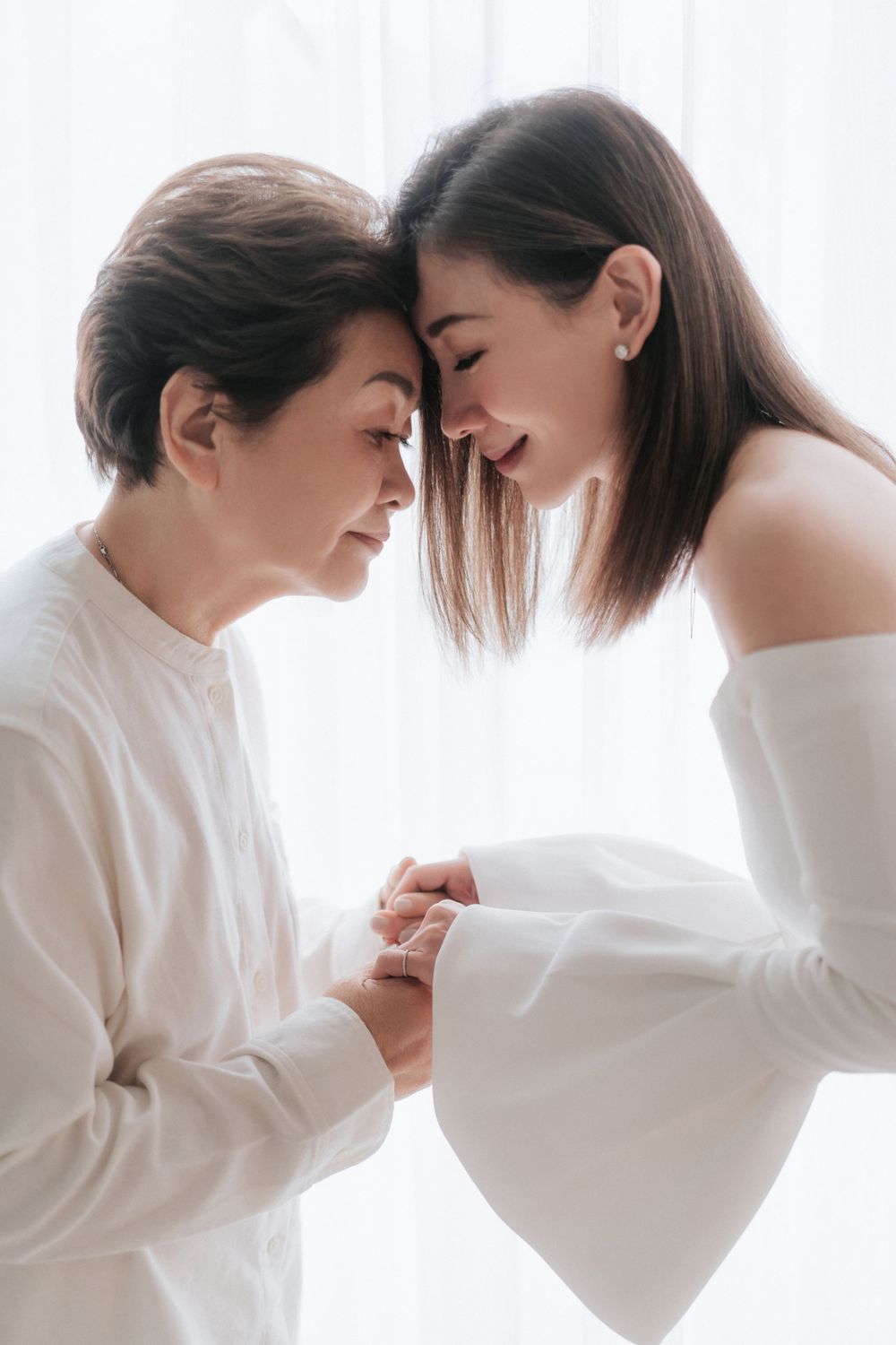 An intimate portrait showing two generations sharing a tender moment in matching white attire.