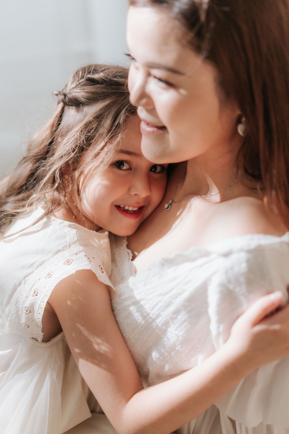 An intimate portrait showing a loving embrace while wearing matching white dresses.