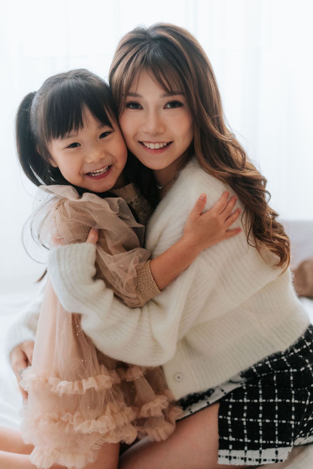 A heartwarming portrait showing affection and laughter in matching cream-colored knitwear.