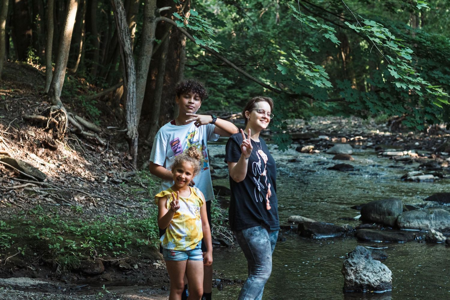 Family enjoying nature walk by creek in wooded area.