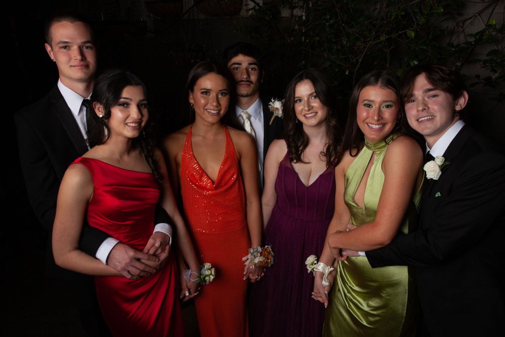 Formal group photo of teens dressed up for prom in colorful dresses and tuxedos.