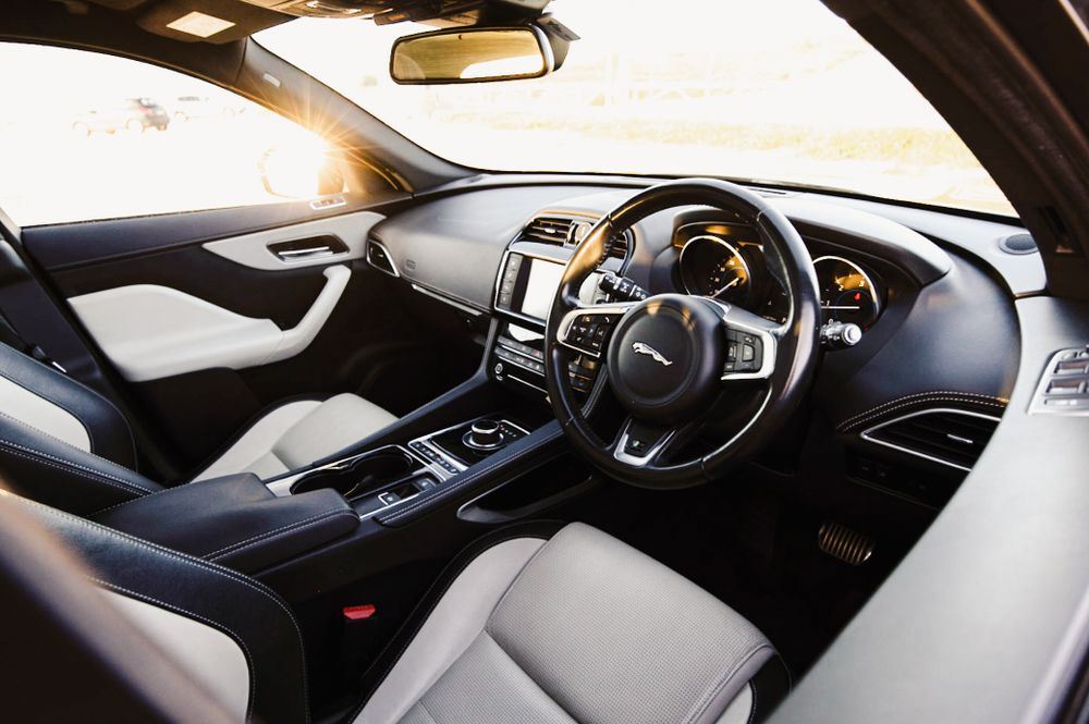 Modern luxury car interior with leather seats, steering wheel and digital dashboard in contemporary design.