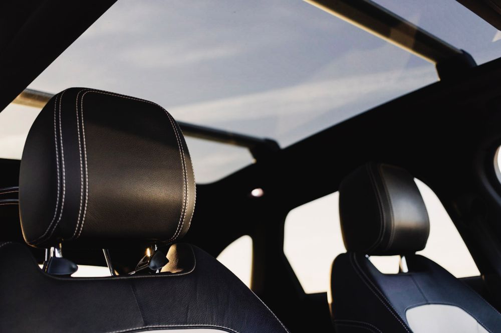 Black leather car headrests with sunroof visible in luxury vehicle interior.