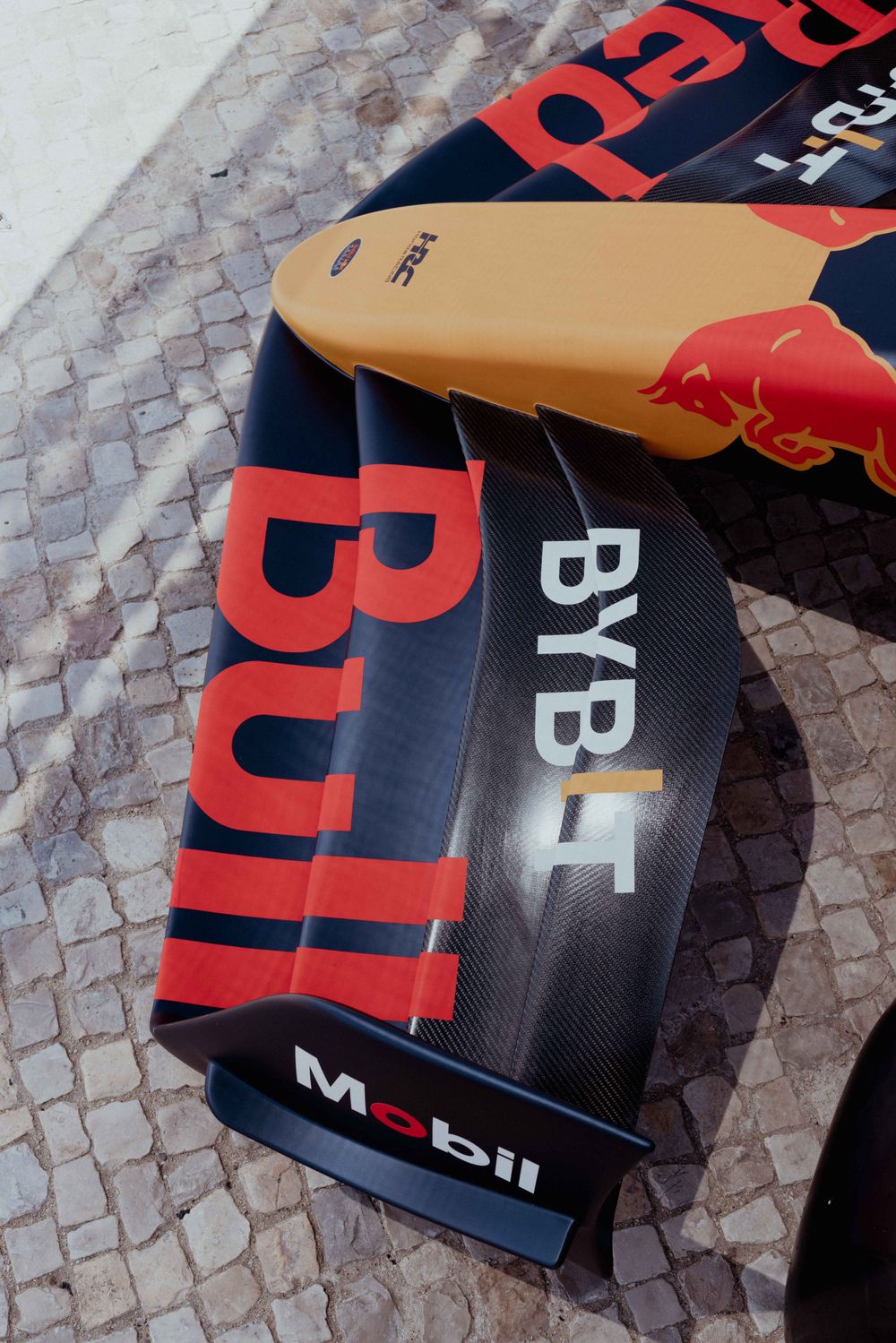 Close-up detail of Red Bull racing car bodywork showing Bybit and Mobil sponsorship logos on dark surface.