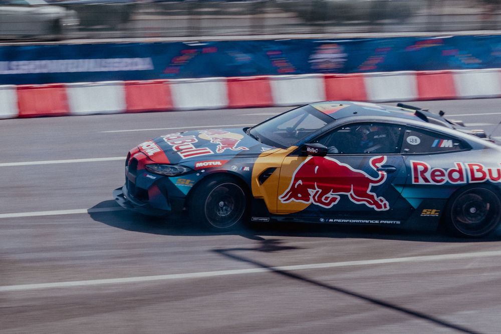 Red Bull branded BMW drifting on a street circuit with dramatic motion blur.