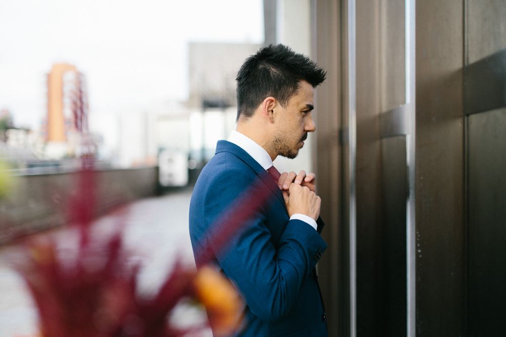 Side profile of groom in blue suit looking contemplatively through window.