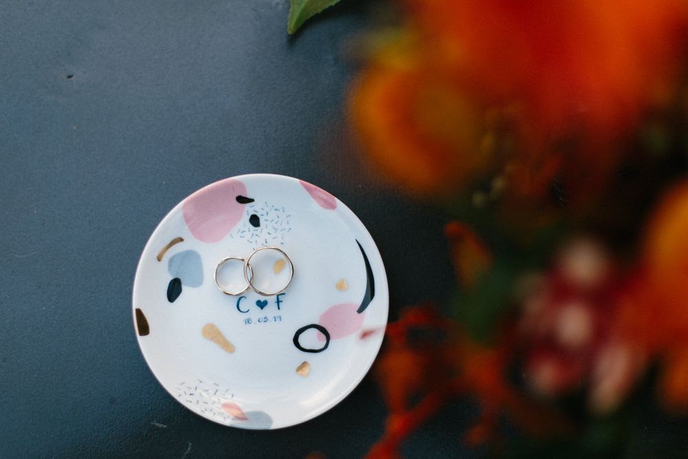 Wedding rings photographed on a decorative plate with soft floral background.