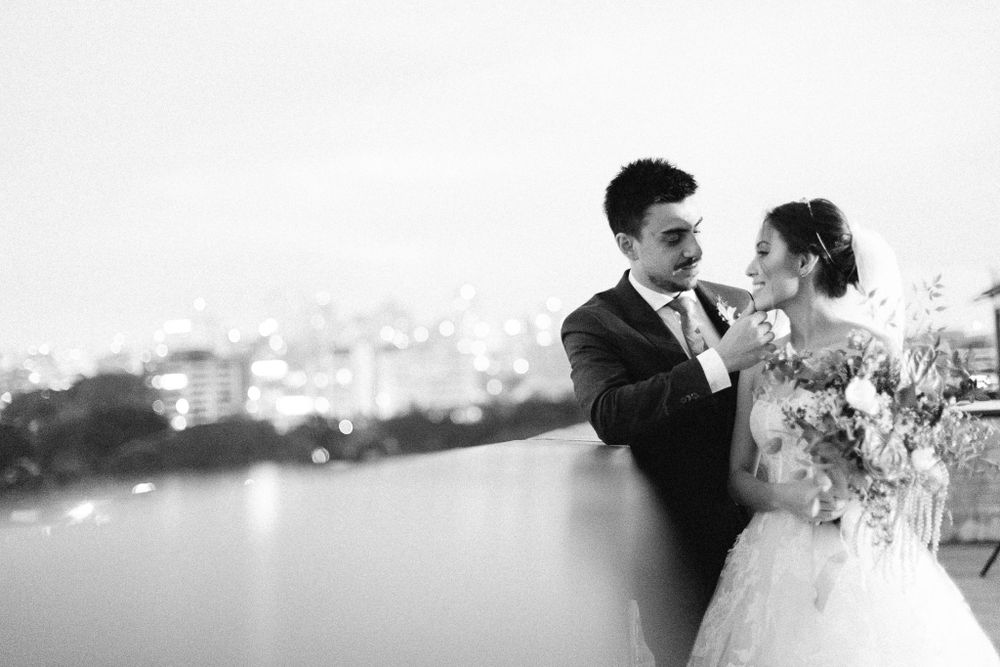 Black and white wedding portrait overlooking a cityscape with water view in the background.