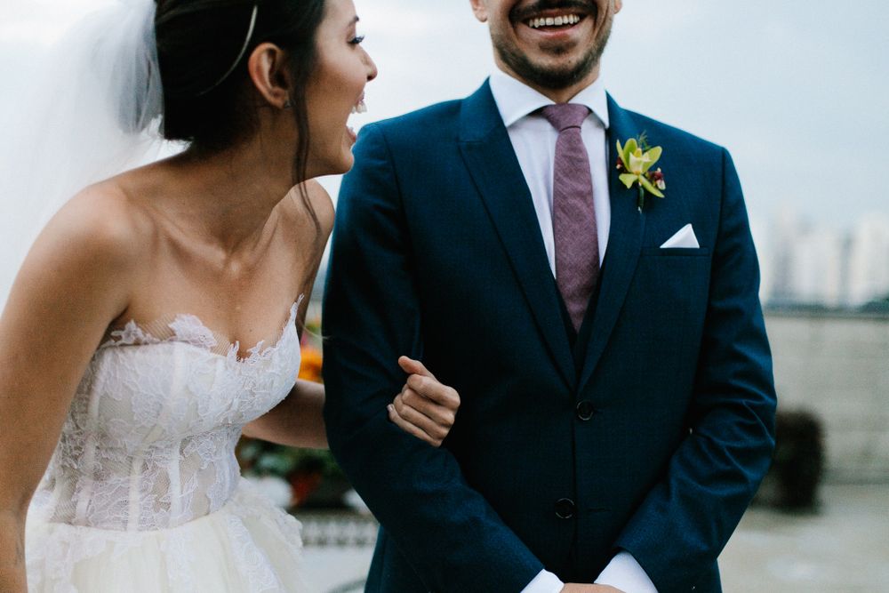 A candid moment of laughter between newlyweds, with the groom in a navy suit.