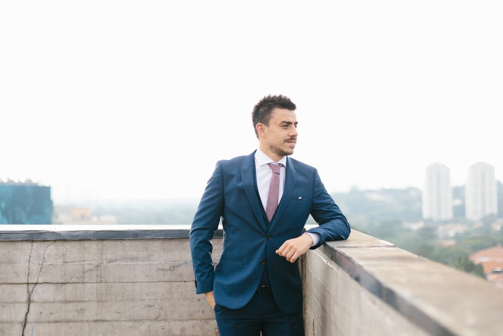 Professional in navy suit and pink tie poses confidently against city backdrop.
