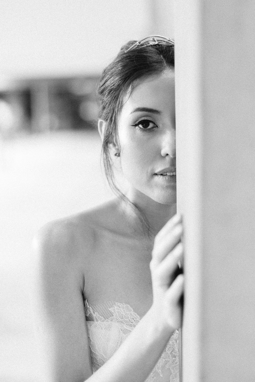 Artistic black and white portrait partially obscured behind a wall.