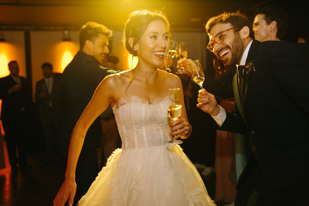 Wedding reception dance party with warm lighting as couple celebrates with drinks.