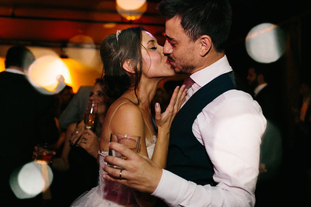 Intimate dance floor moment between newlyweds with warm ambient lighting and bokeh effects.
