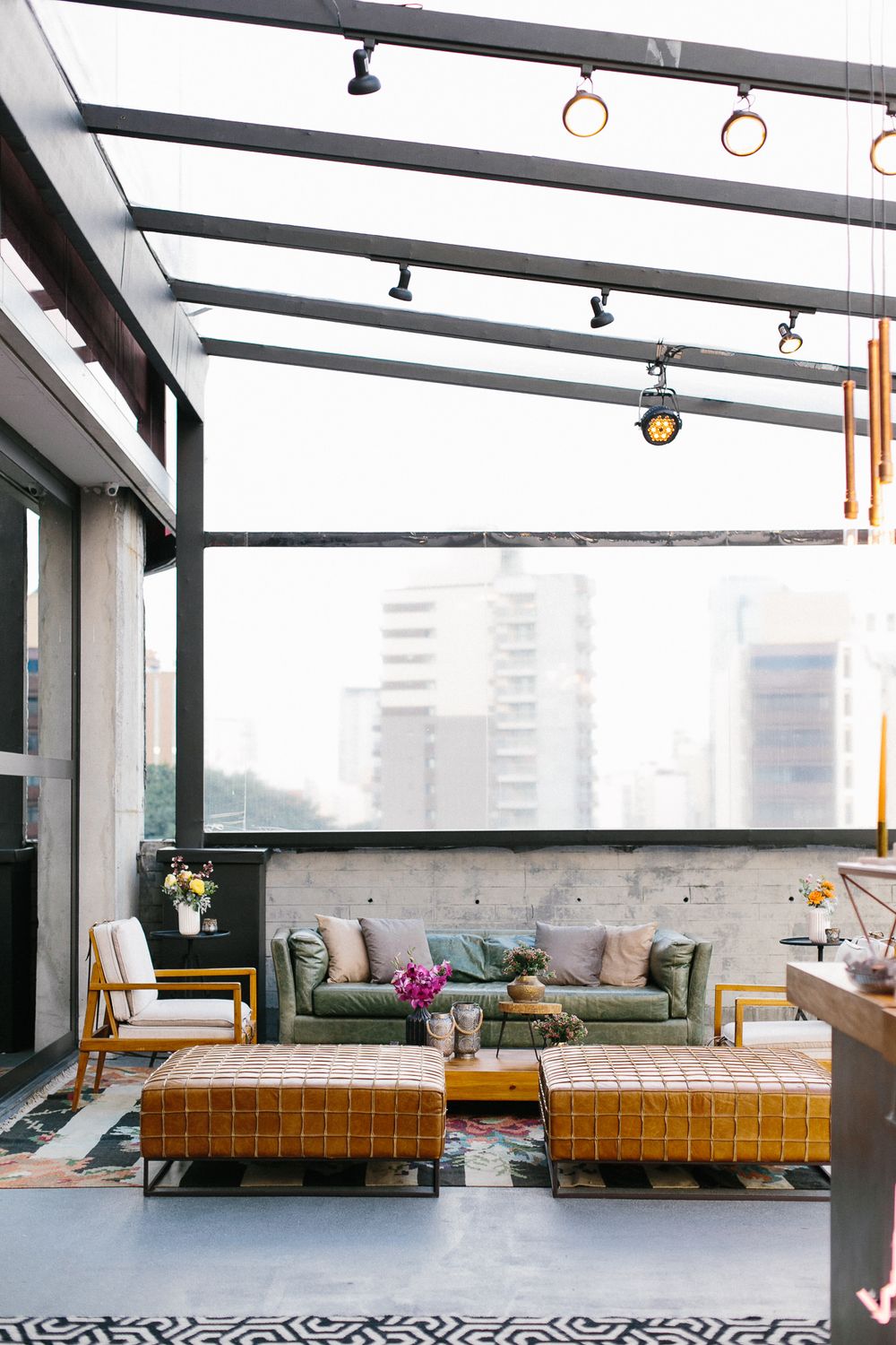 Modern rooftop lounge area with glass ceiling and comfortable seating arrangement.