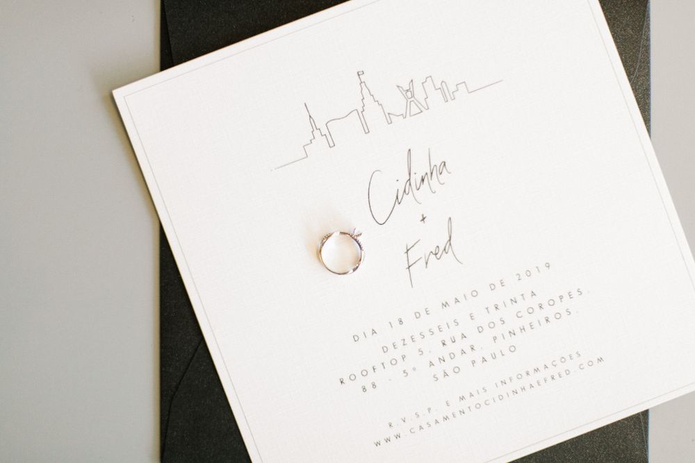 White wedding invitation with gold rings and elegant calligraphy on a black background.