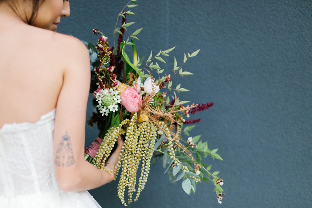Back view of bride holding a wild and romantic cascading bouquet with pink flowers.