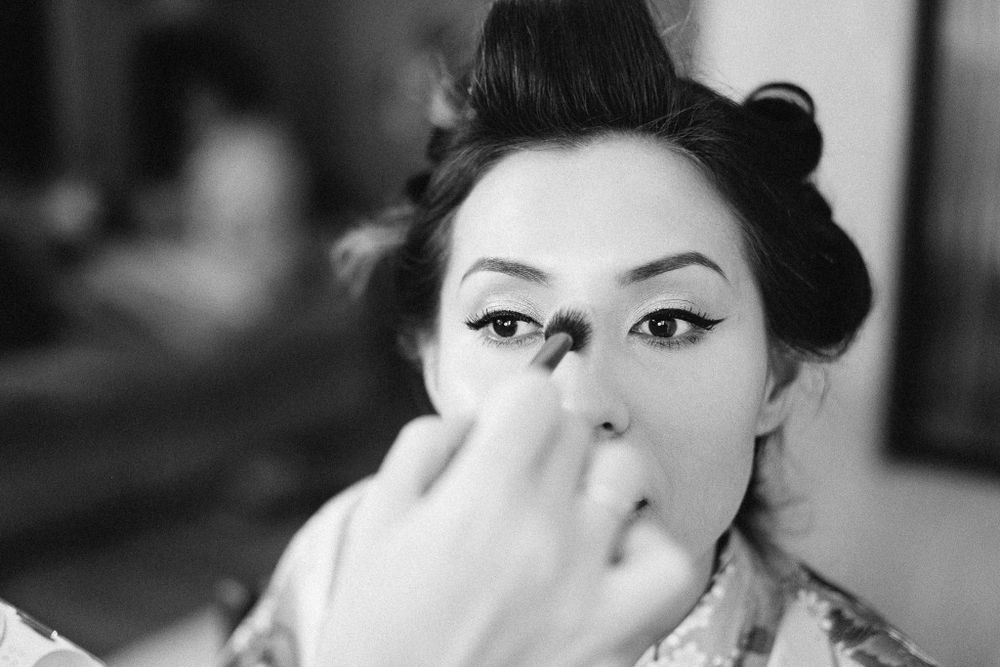 Black and white close-up of someone applying makeup with a brush.