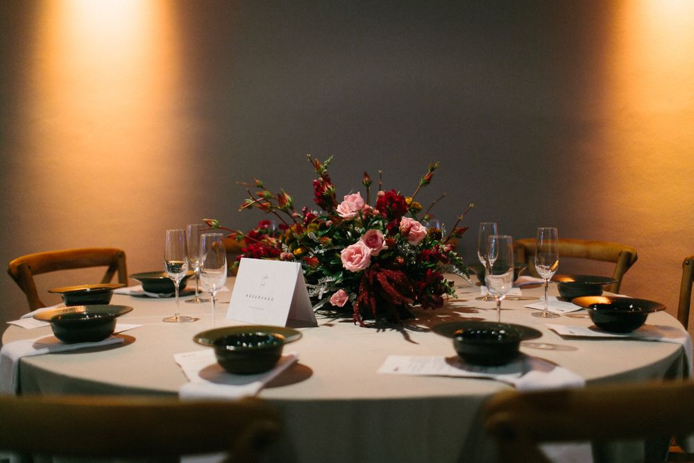 Elegant wedding table setting with floral centerpiece and place settings in warm ambient lighting.