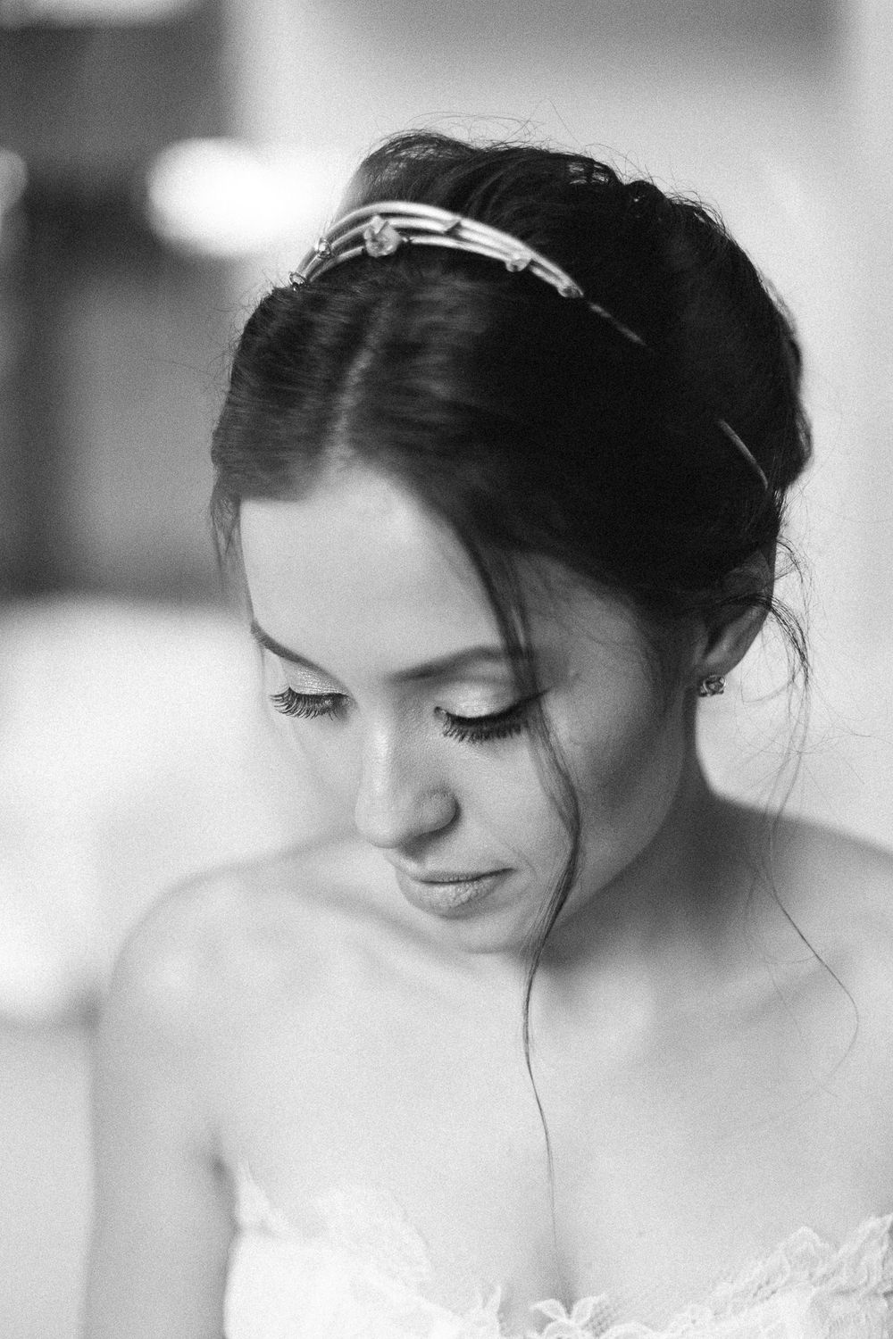 Black and white portrait of a bride wearing a delicate headpiece and lace wedding dress.