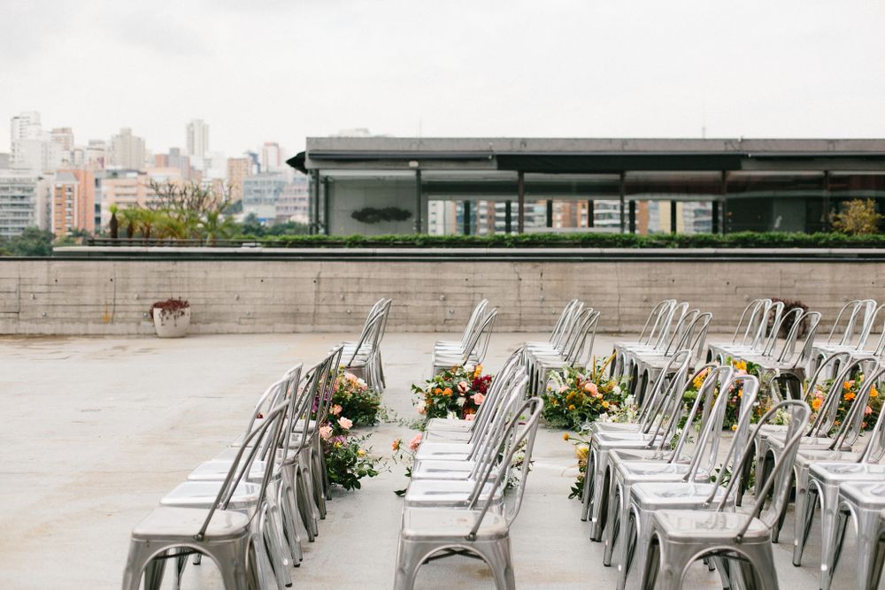 Modern rooftop wedding venue setup with silver chairs and city skyline in background.