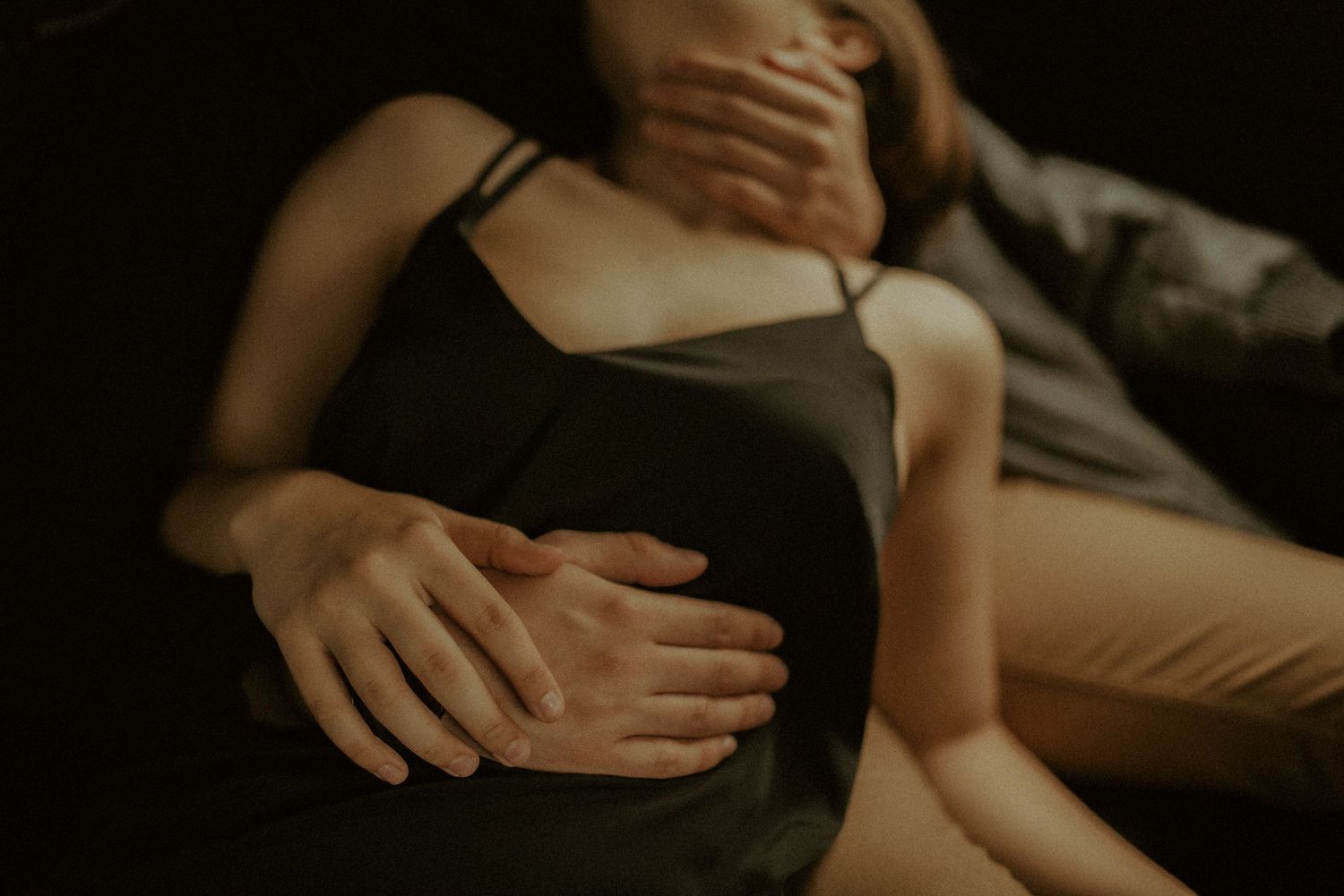 Close-up of hands tenderly embracing in moody lighting.