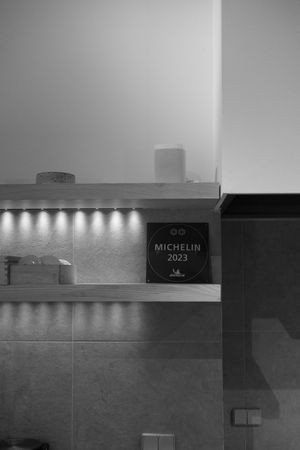 A modern interior wall with illuminated shelves and a Michelin 2023 plaque mounted in black and white.