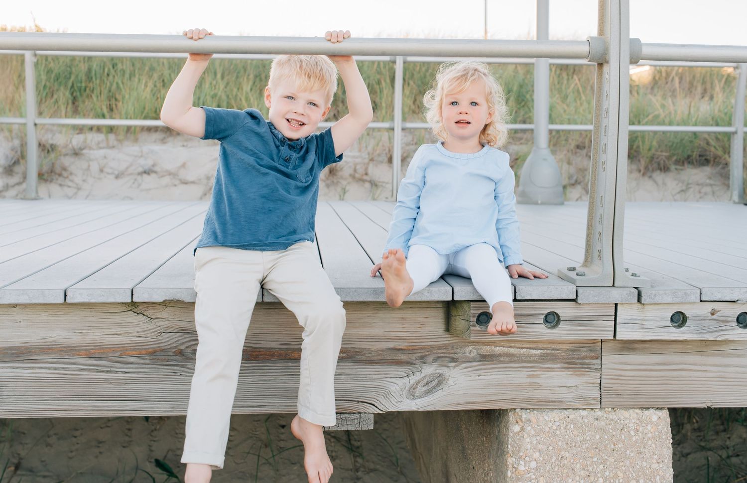 A brother and sister sitting on the boardwalk on a summer night.