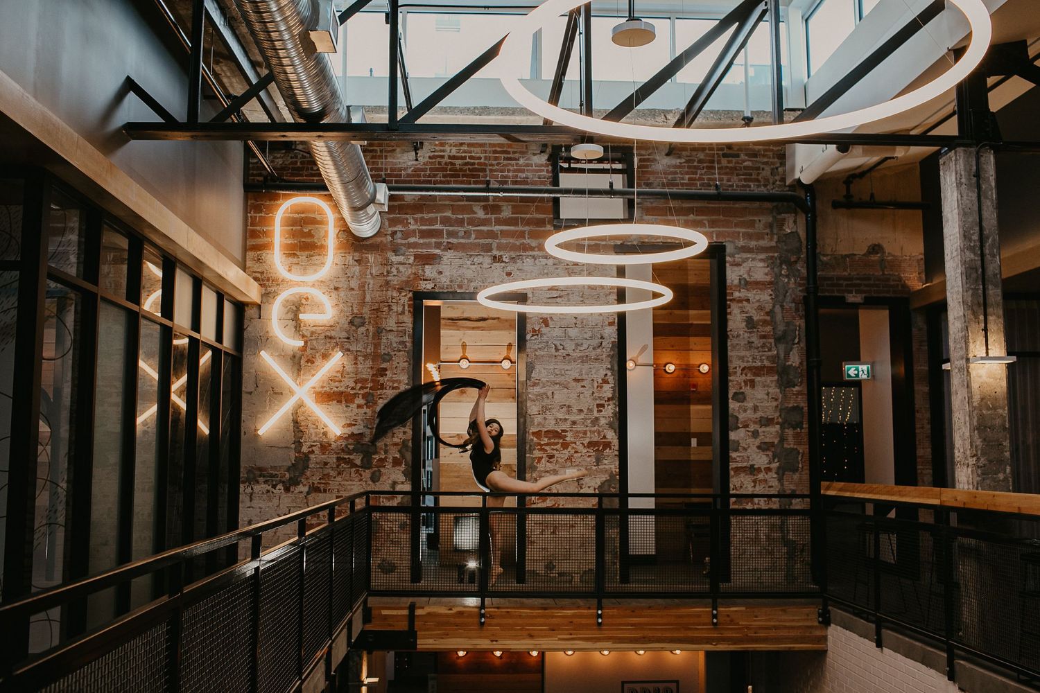 Industrial style interior with neon sign and circular lighting fixtures.