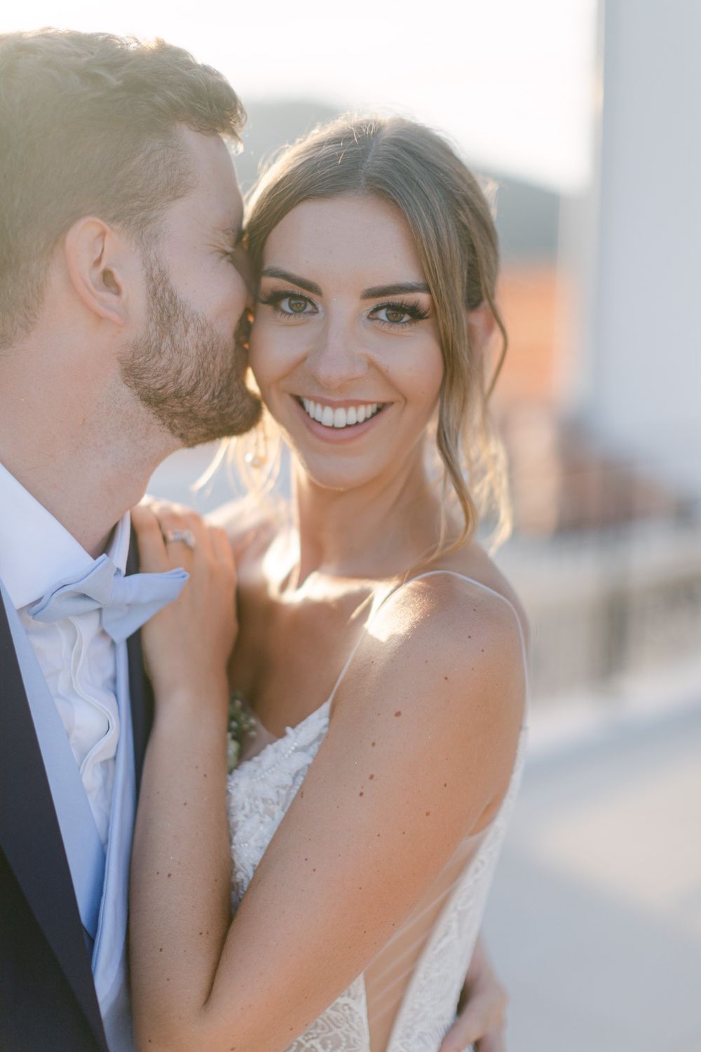 Portrait romantique de mariage du couple s’enlaçant au coucher du soleil, la mariée portant une robe en dentelle au Castel Bay