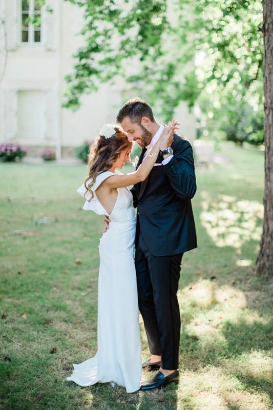 La mariée et le marié partagent un moment de danse intime dans un jardin.