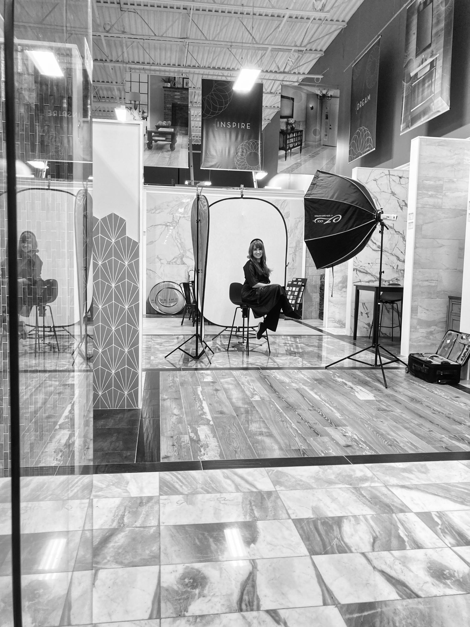 Studio photography setup with lighting equipment and backdrop visible through glass.