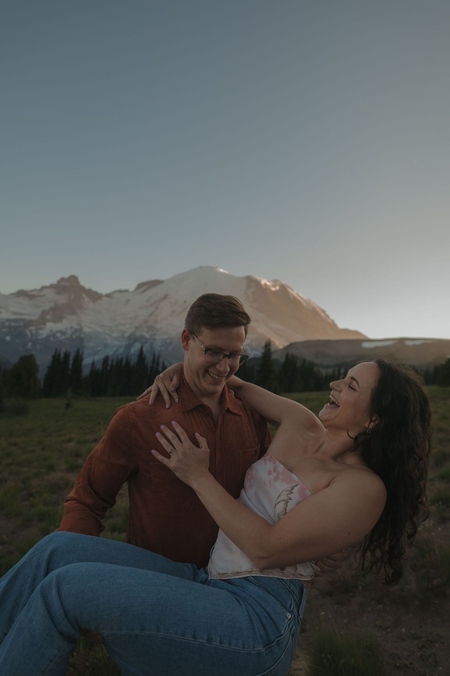 A joyful moment captured between two people in front of a stunning mountain landscape.