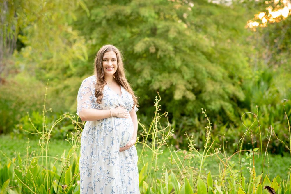 proud mama. Expecting mother in flowing gown at Houston Arboretum during Houston maternity photography session at sunset