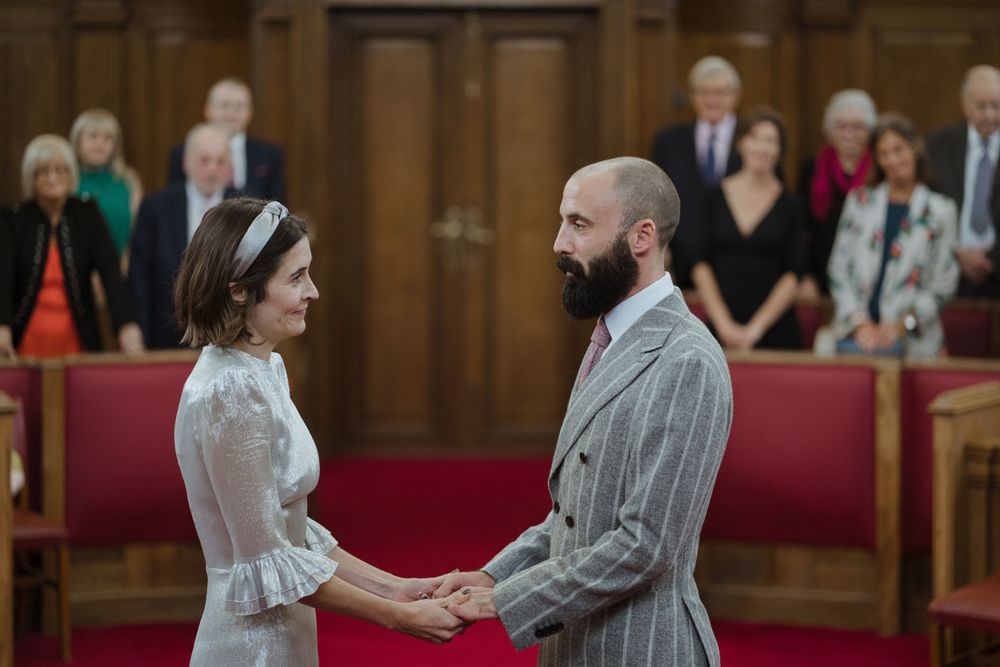 Wedding ceremony in wood-paneled room with red seating.