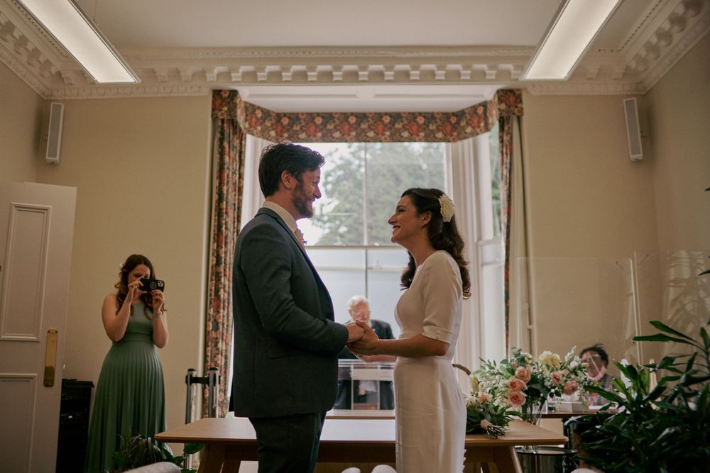 An intimate indoor wedding ceremony moment by a window with elegant decor.