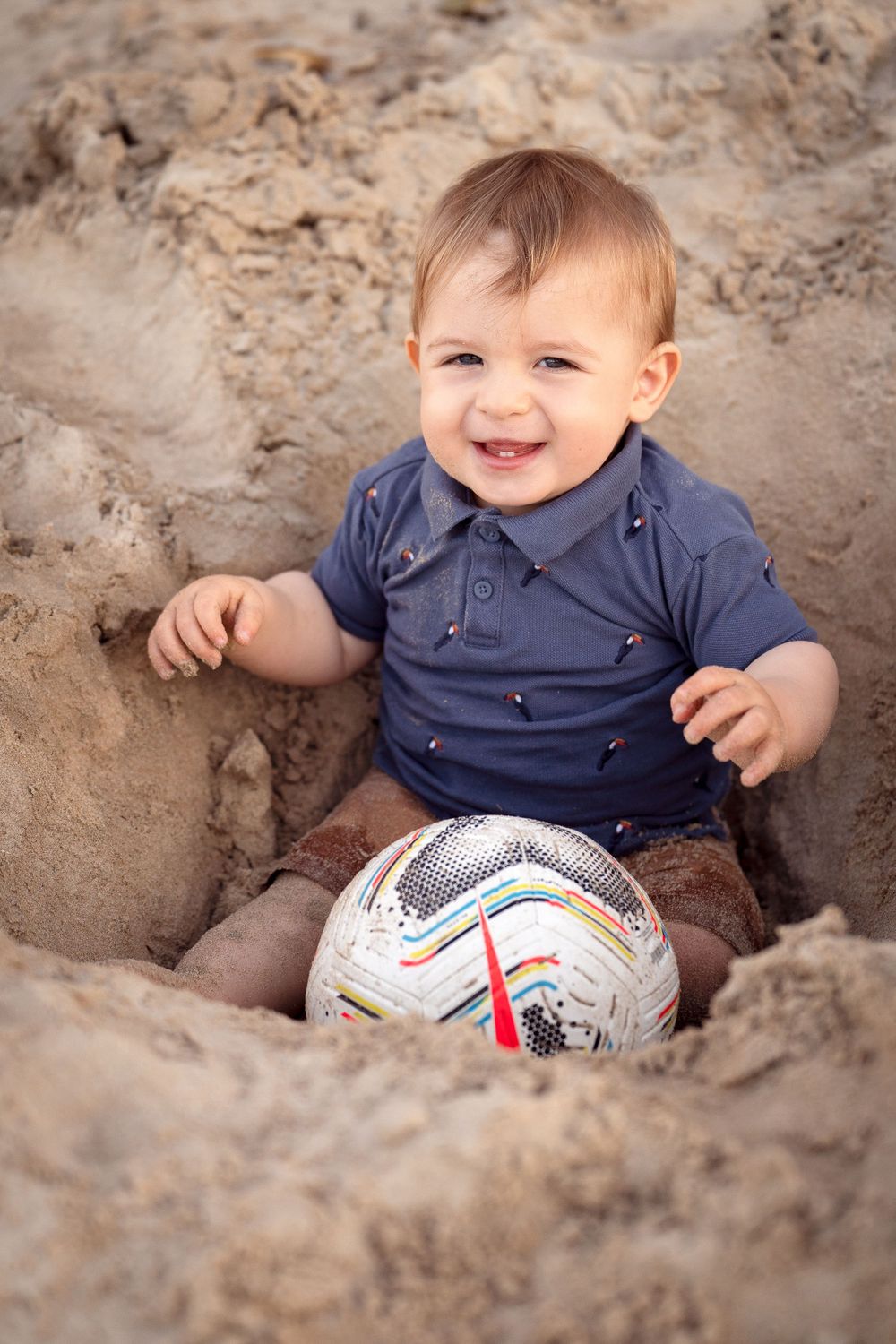 baby boy is happily posing with a ball at Mosman Balmoral Beach during a family photoshoot
