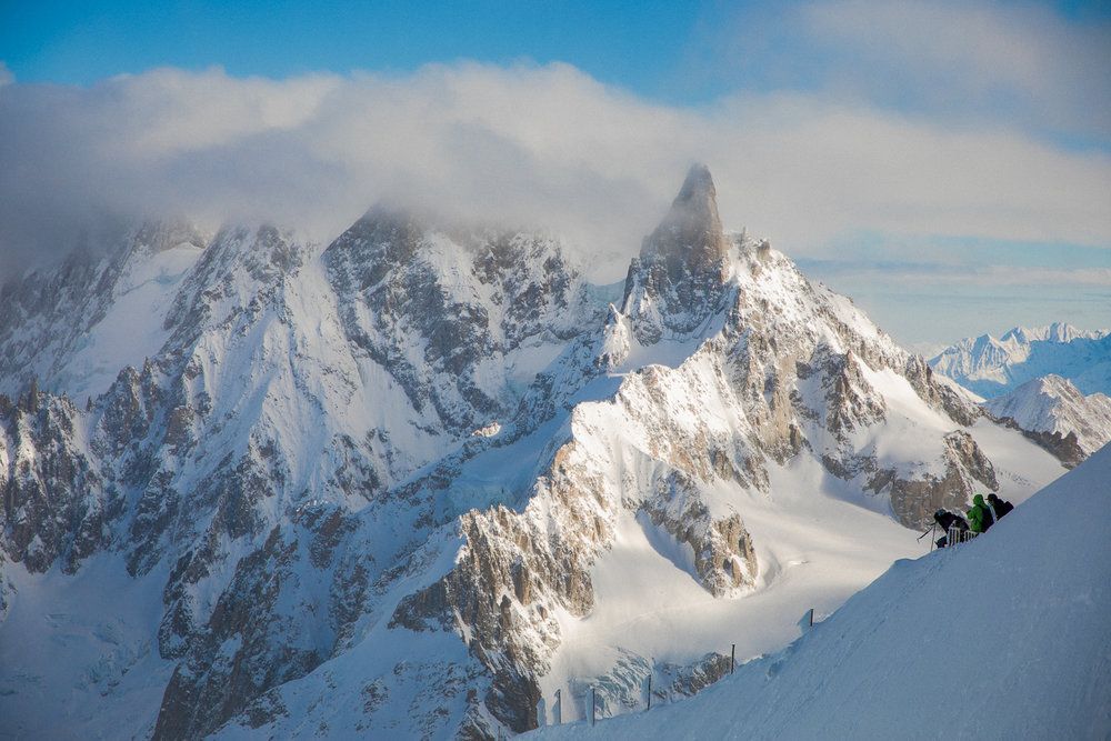 Dramatic snow-covered mountain peaks rise into misty clouds in winter.